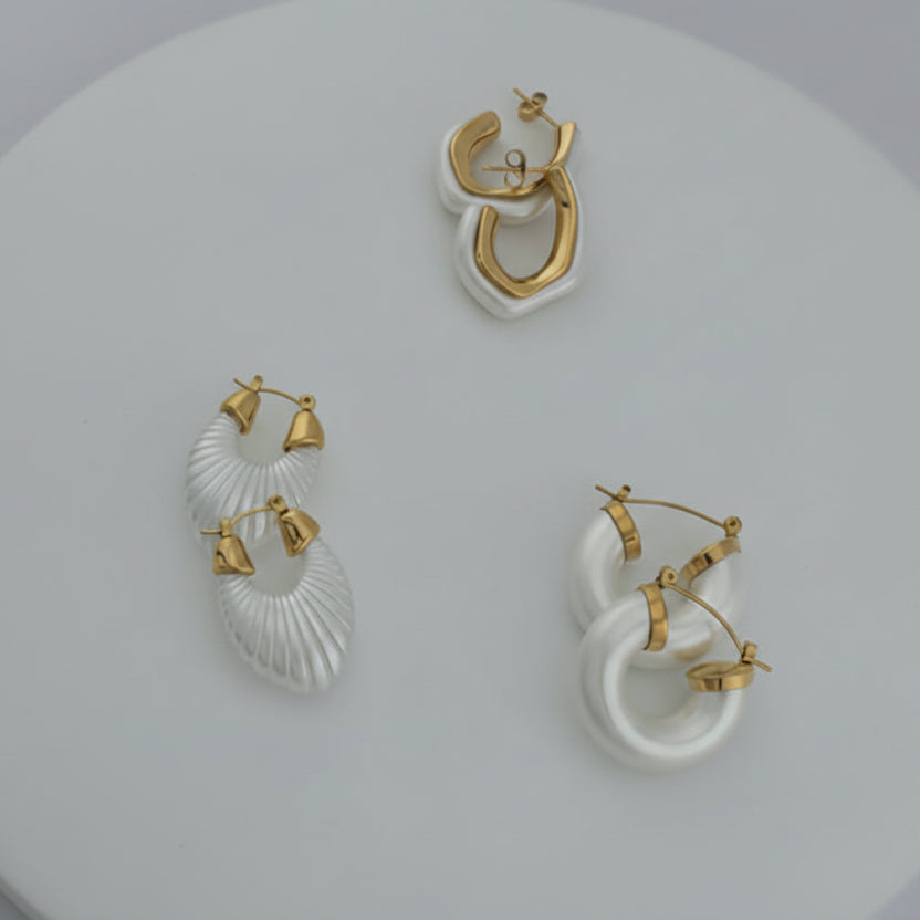 3 Pair of different gold and white hoop earrings on a light gray background