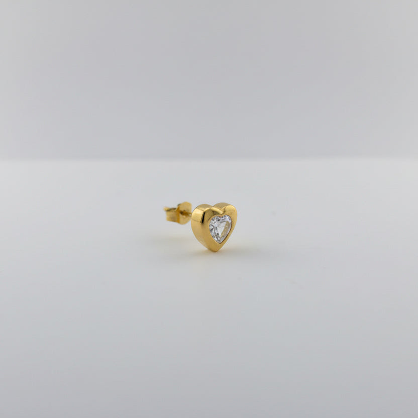 Gold earring with a heart-shaped gemstone on a light gray background
