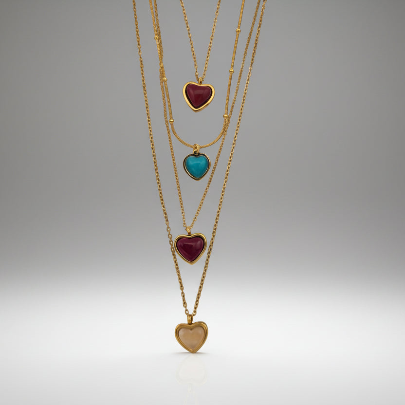 Gold necklaces with heart-shaped gemstones on a white background