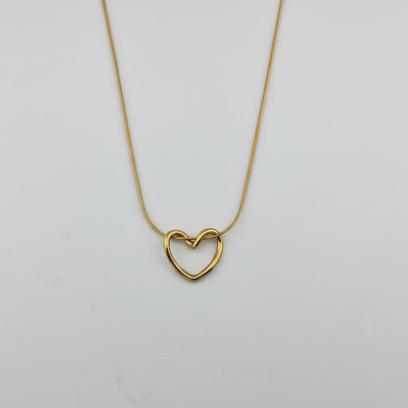 Gold heart-shaped necklace on a light gray background