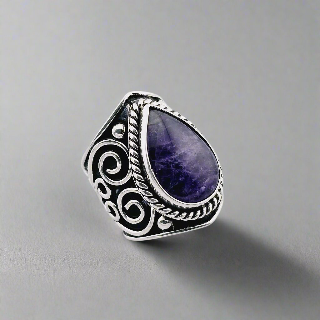 Silver ring whit a big stone of amethyst and decorations all around.