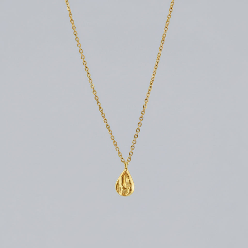 Gold teardrop pendant necklace on a light gray background