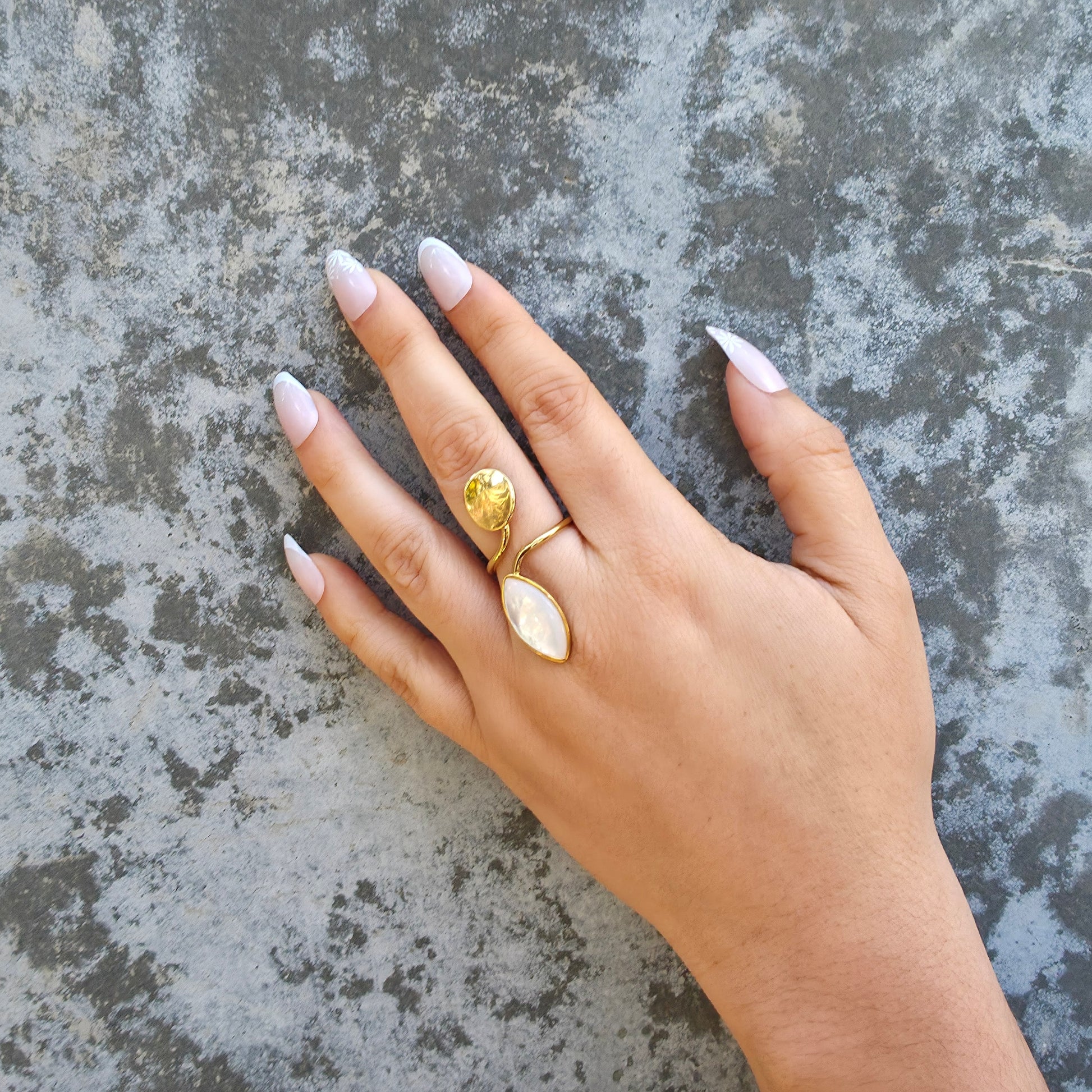 Hand wearing a gold ring on a textured gray surface