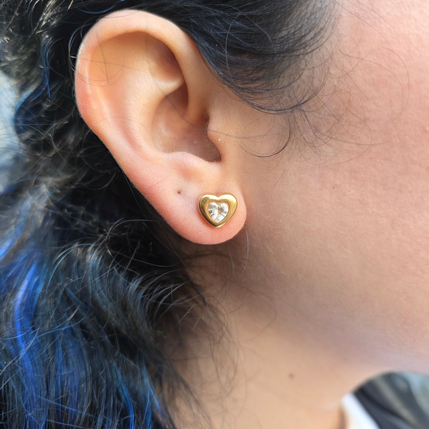 Close-up of an ear with a heart-shaped gold earring.