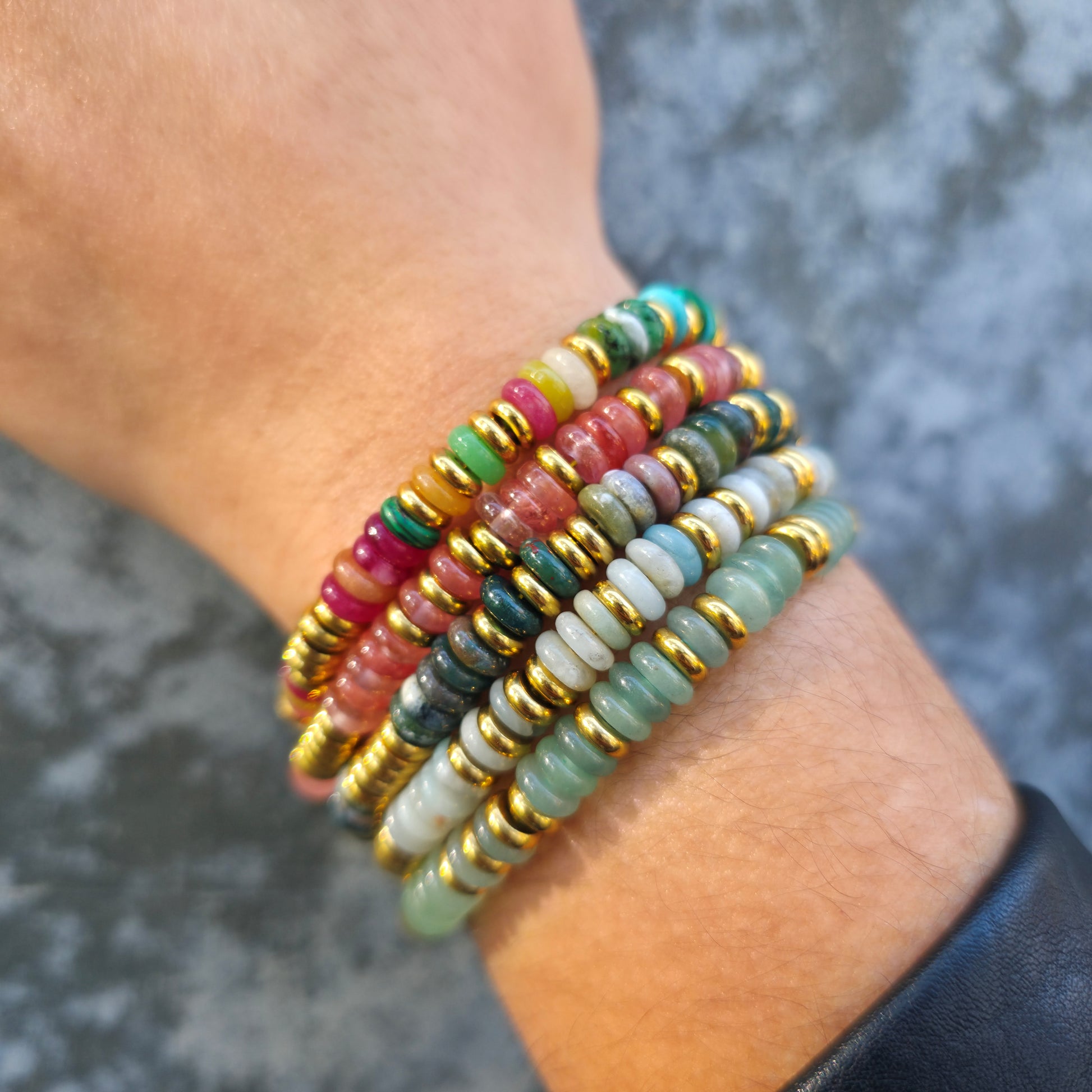 Multicolored beaded bracelets on a wrist with a blurred background