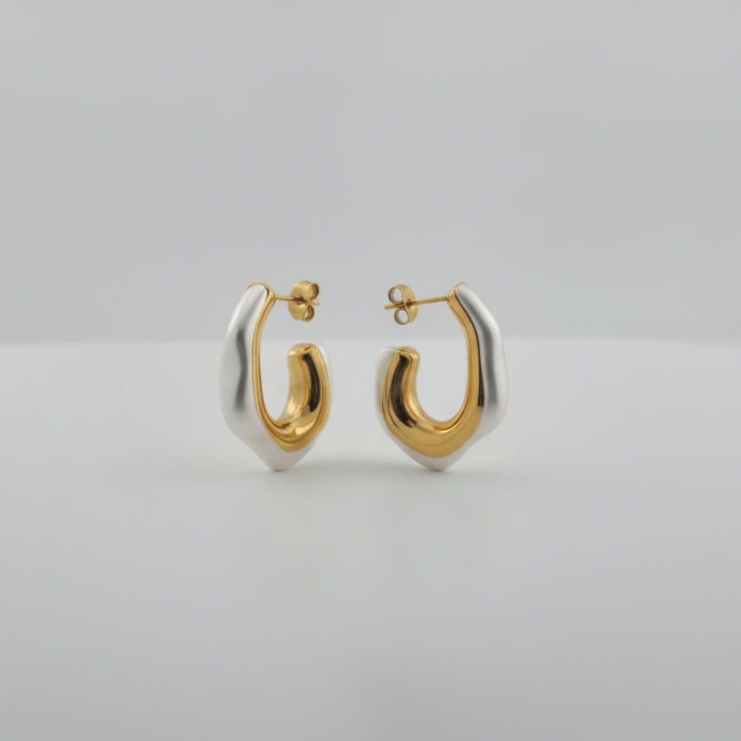 Pair of gold and silver hoop earrings on a light gray background