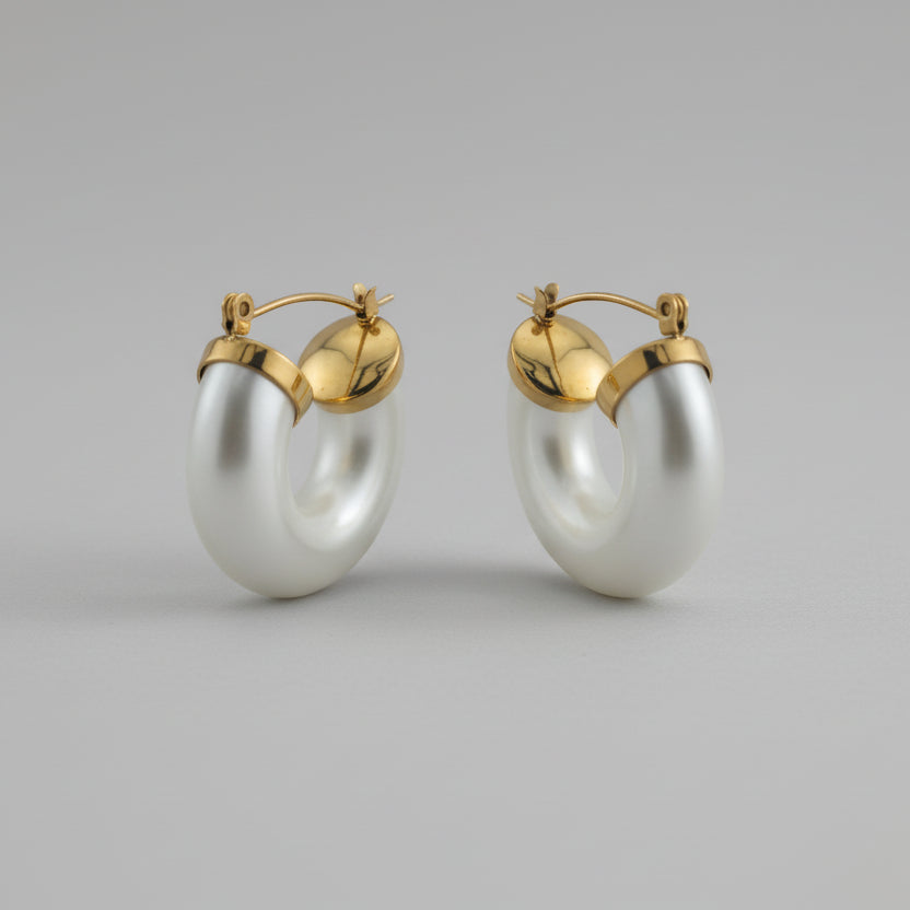 Pair of gold hoop earrings with white pearls on a gray background