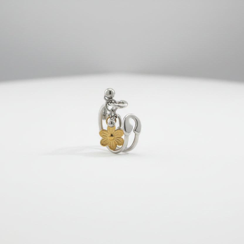 Silver ring with a gold flower charm on a light gray background