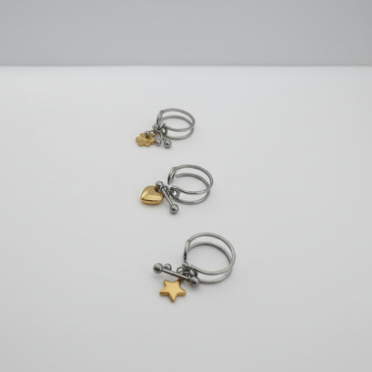 Three silver rings with gold charms on a light gray background