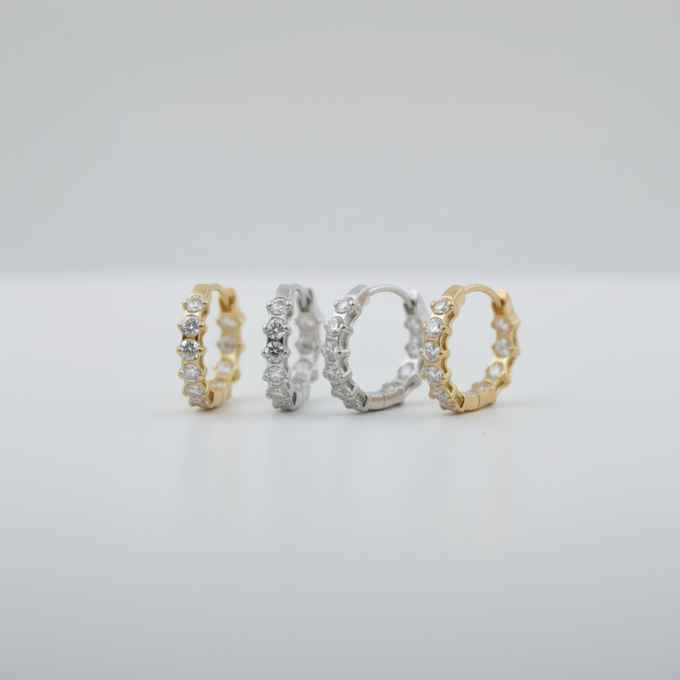 two pairs of hoop earrings in gold and silver on a light gray background