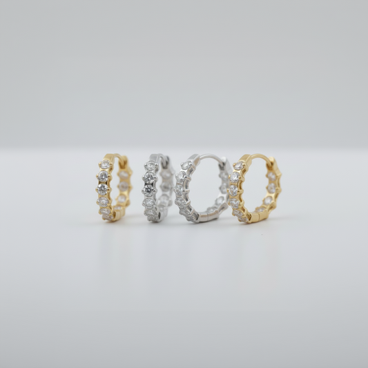 two pairs of hoop earrings in gold and silver on a light gray background