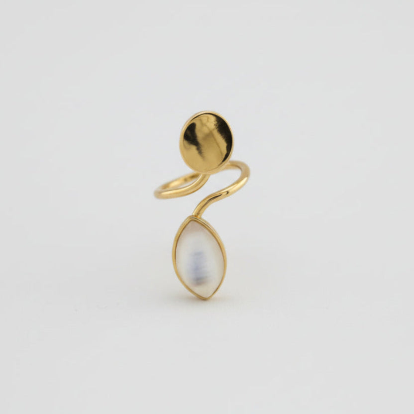 Gold ring with a teardrop-shaped pearl on a light gray background