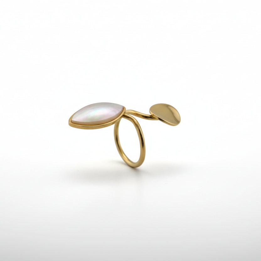 Gold ring with a white stone on a light gray background