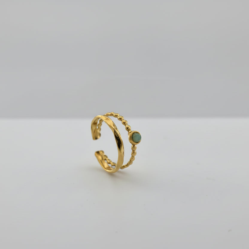 Gold ring with a green stone on a gray background