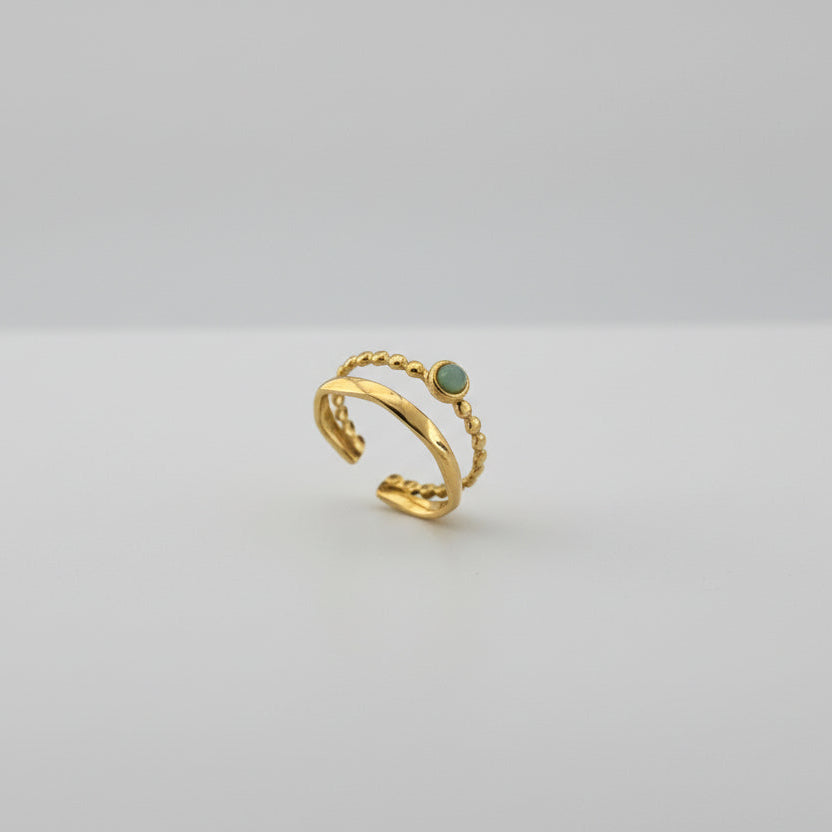 Gold ring with a green gemstone on a white platform
