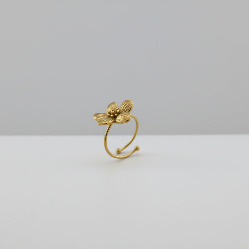Gold ring with a flower design on a light gray background