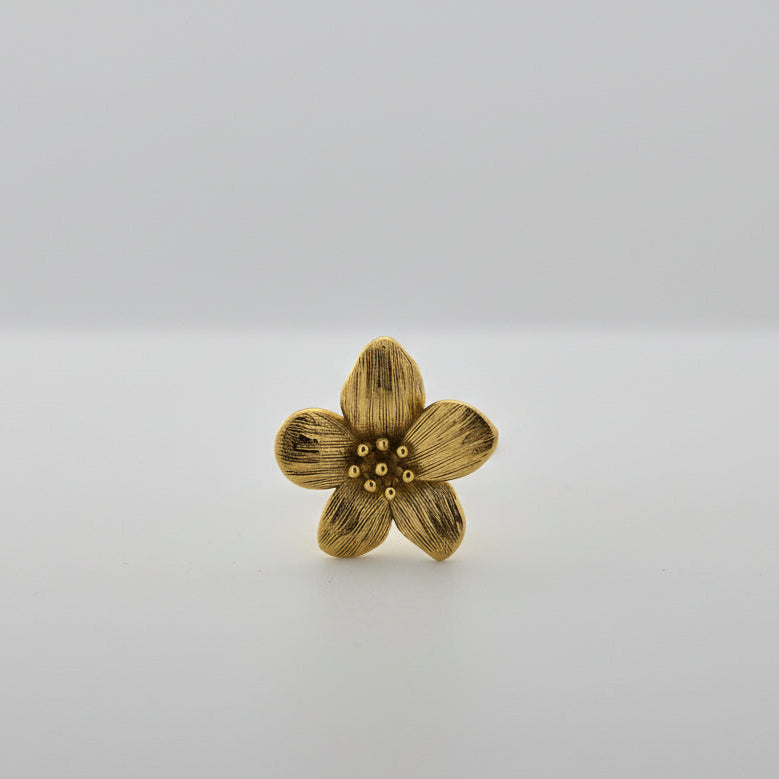 Gold flower-shaped ring on a white surface