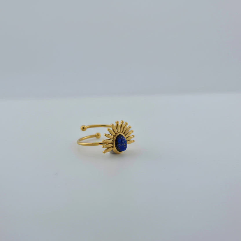 Gold ring with a blue gemstone on a white background
