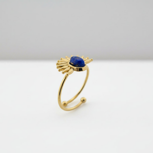 Gold ring with a blue gemstone on a white background