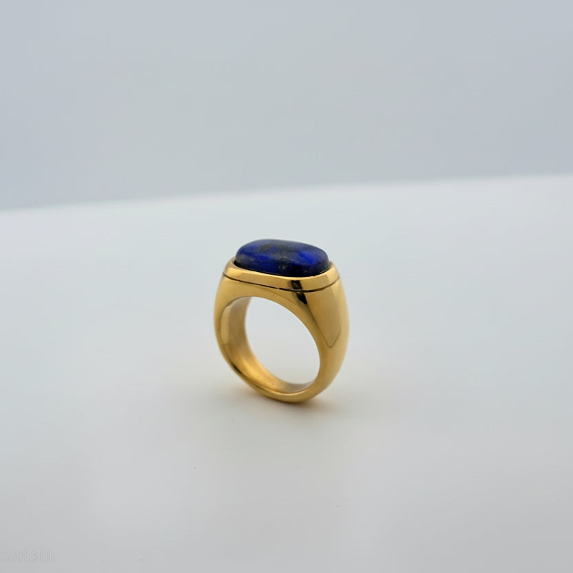 Gold ring with a blue stone on a white background