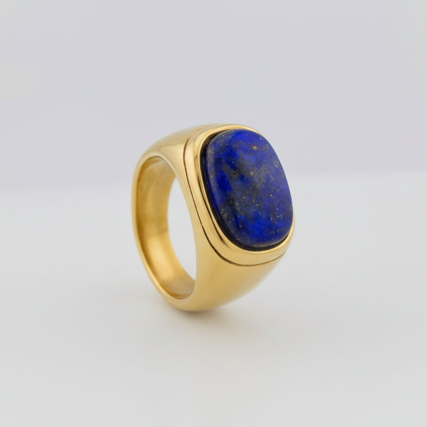 Gold ring with a blue stone on a gray background