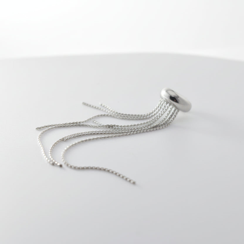 Silver chain necklace on a white surface with a gray background