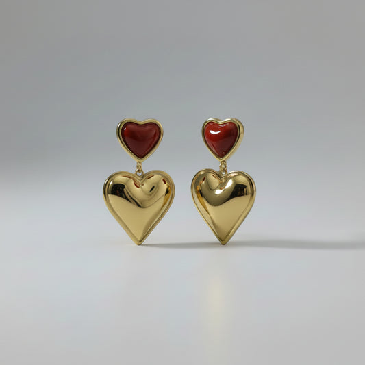 Gold earring with red heart on a white card