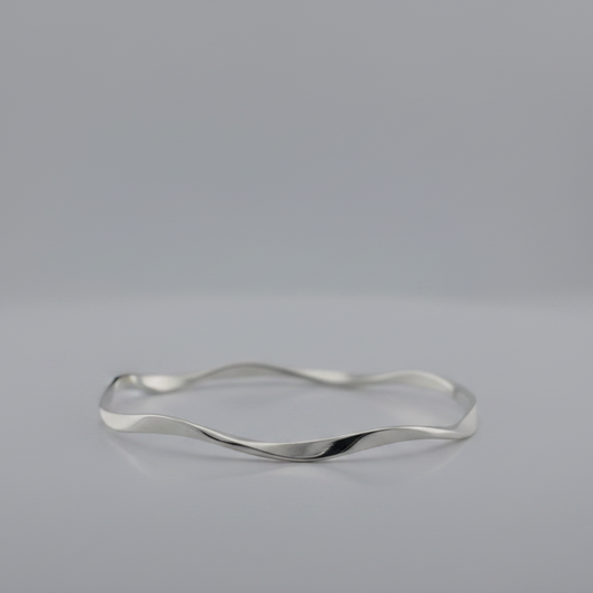 Silver bracelet with a wavy design on a gray background