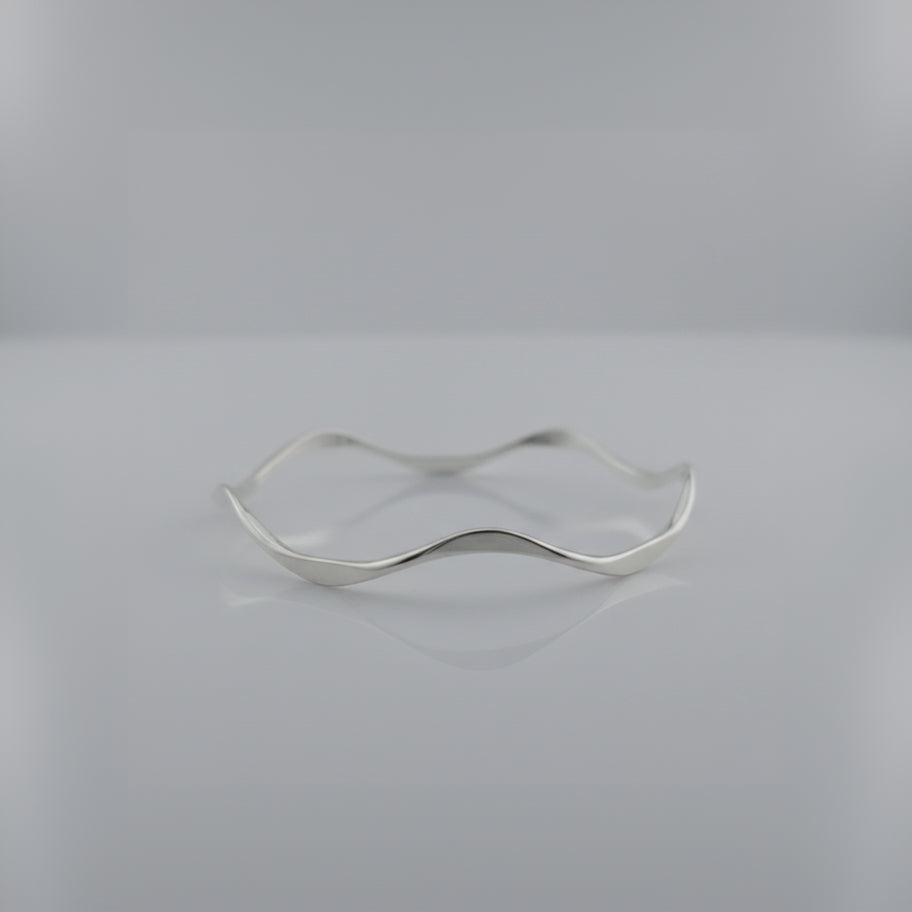 Silver ring with a wavy design on a light gray background