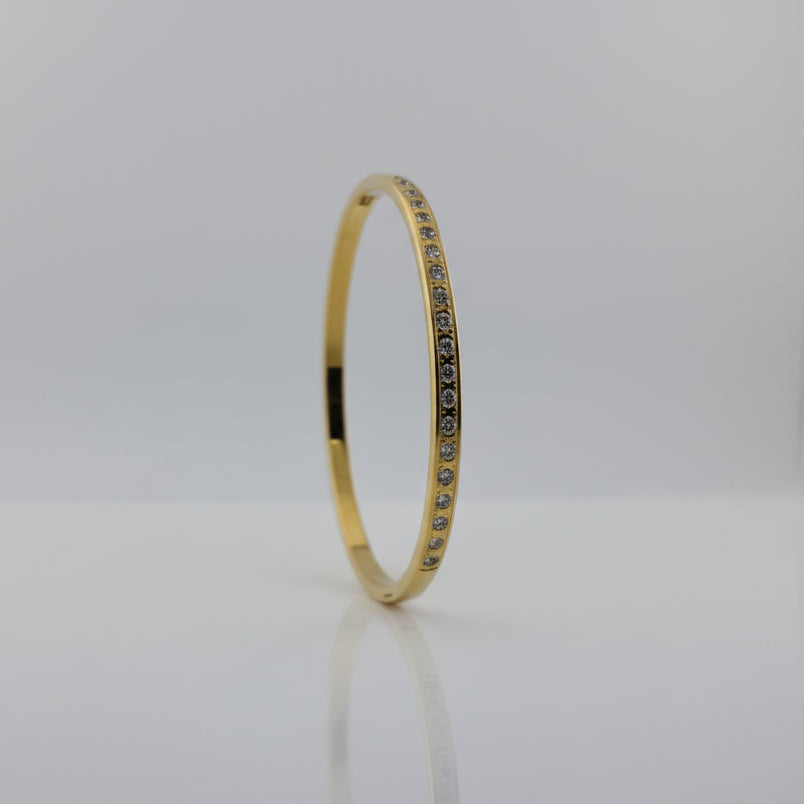 Gold bracelet with embedded stones on a white background
