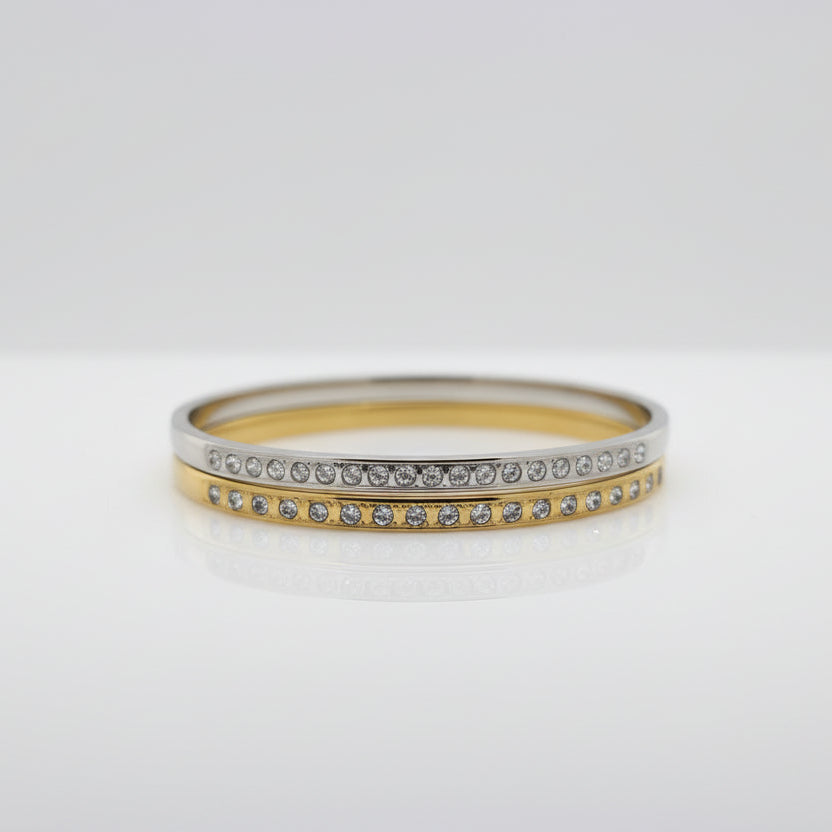 Gold and silver cuff bracelets with embedded cubic zirconia stones on a white background.