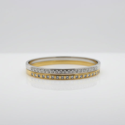 Gold and silver cuff bracelets with embedded cubic zirconia stones on a white background.