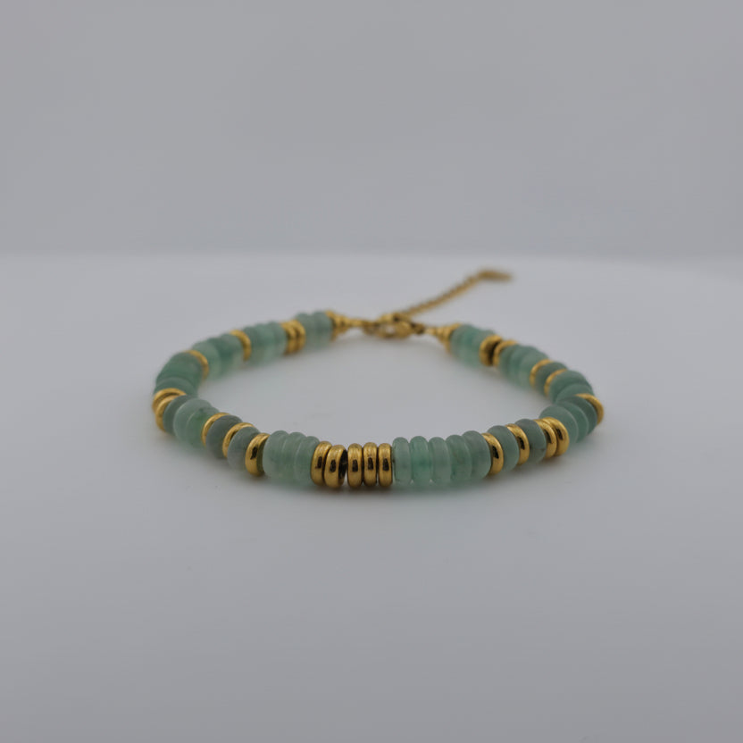 Green beaded bracelet with gold accents on a white background