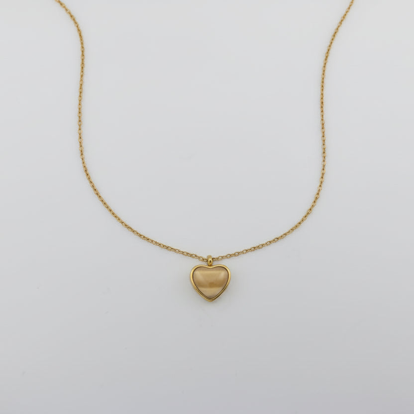 Gold heart-shaped pendant necklace on a light gray background