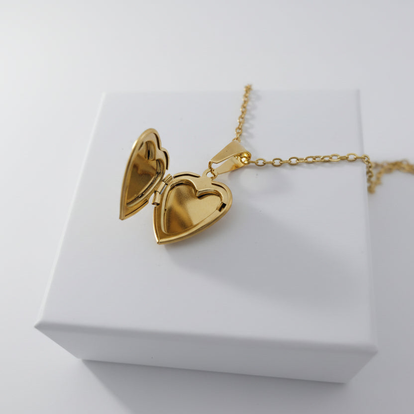 Gold heart-shaped locket on a white surface