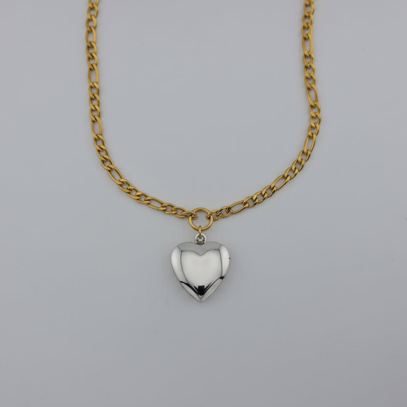 Gold chain necklace with a heart-shaped pendant on a gray background