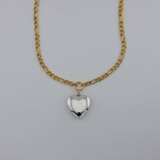 Gold chain necklace with a heart-shaped pendant on a gray background
