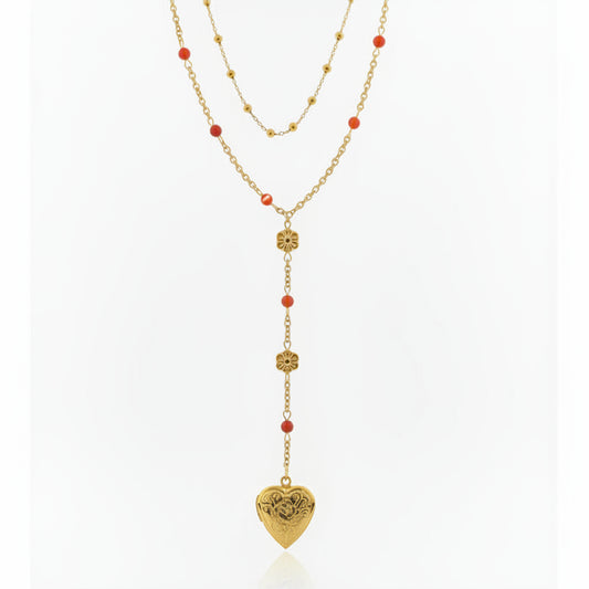 Gold necklace with heart-shaped pendant and red beads on a gray background