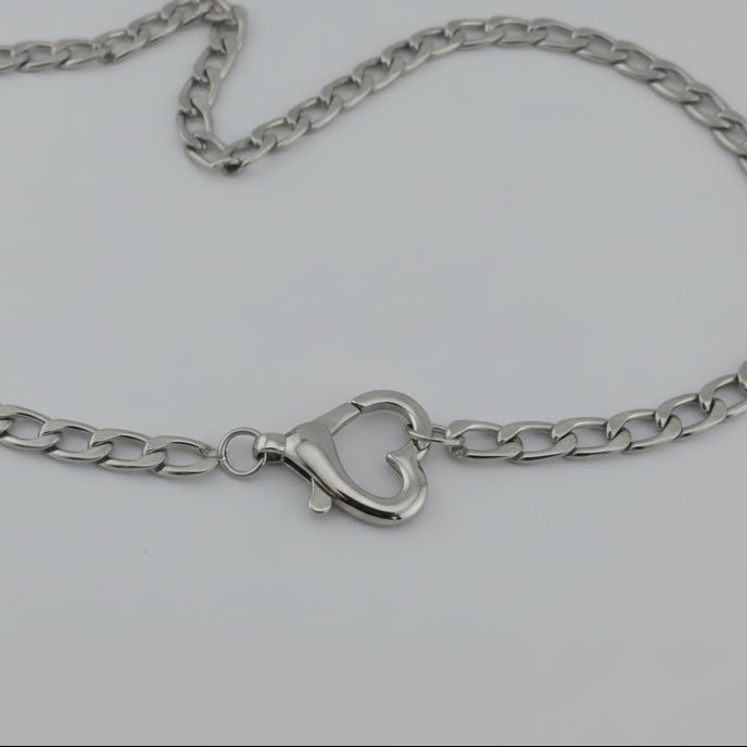 Silver chain necklace with a heart-shaped clasp on a light gray background