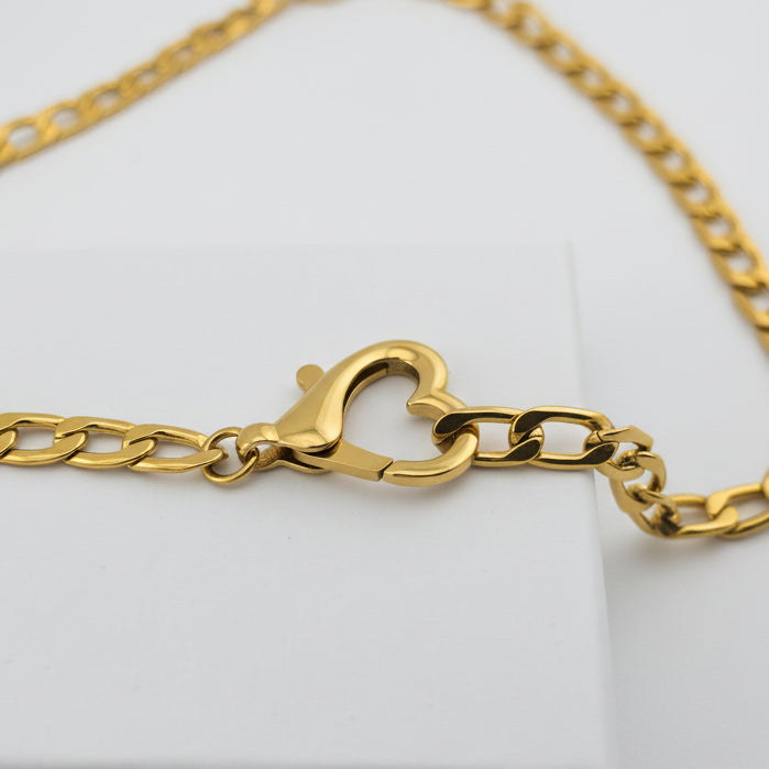 Gold chain with a heart-shaped clasp on a white box