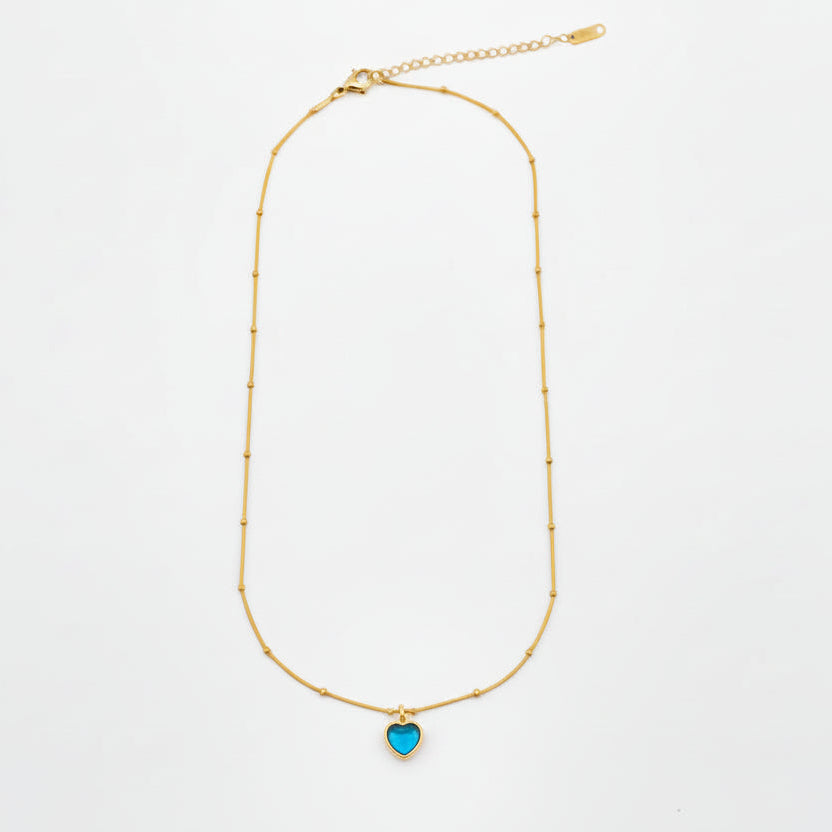 Gold necklace with a blue pendant on a white background