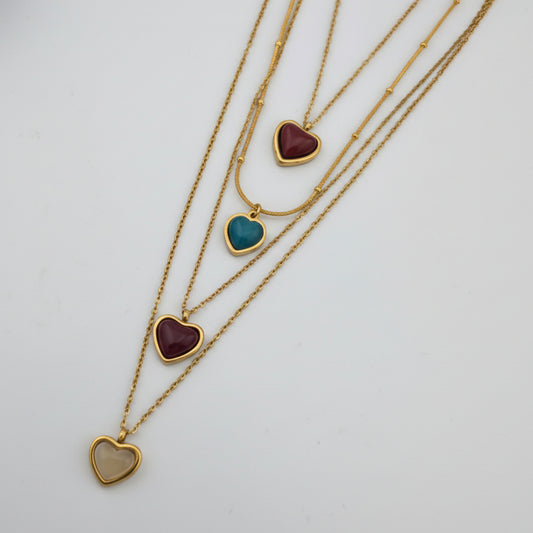 Three gold necklaces with heart-shaped pendants on a white background