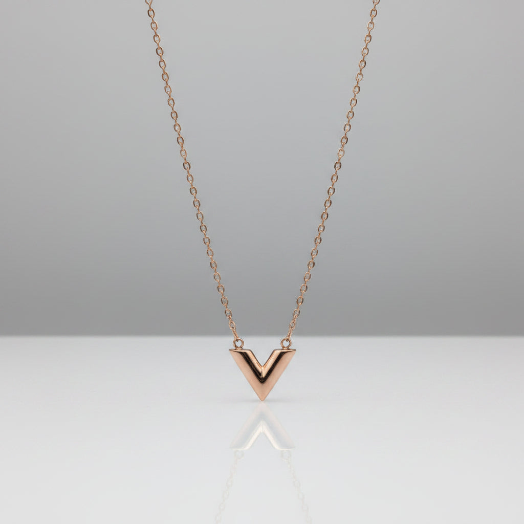 Rose gold necklace with a V-shaped pendant on a light gray background