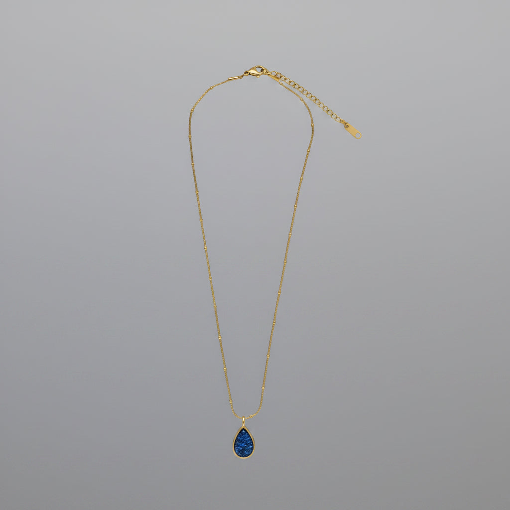 Gold necklace with a blue pendant on a white background