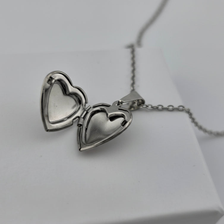 Silver heart-shaped necklace on a white box with a light gray background