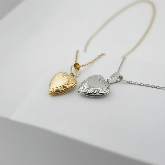 Two heart-shaped pendants on chains against a white box background