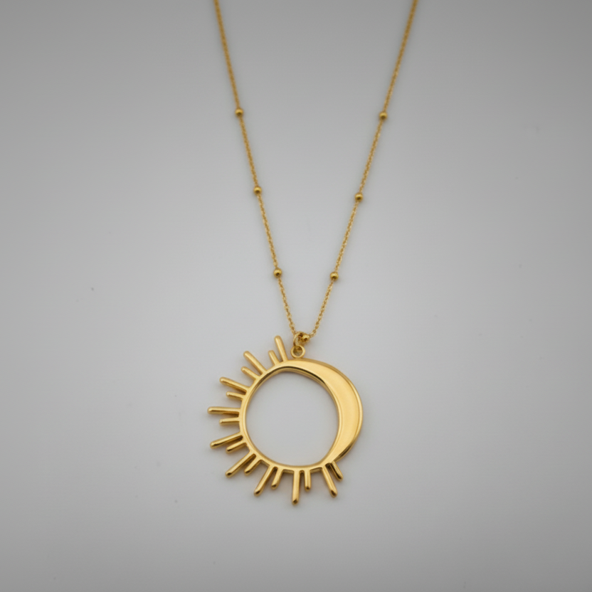 Gold necklace with a sun-shaped pendant on a gray background