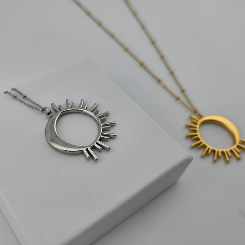 Silver sun-shaped necklace on a white surface