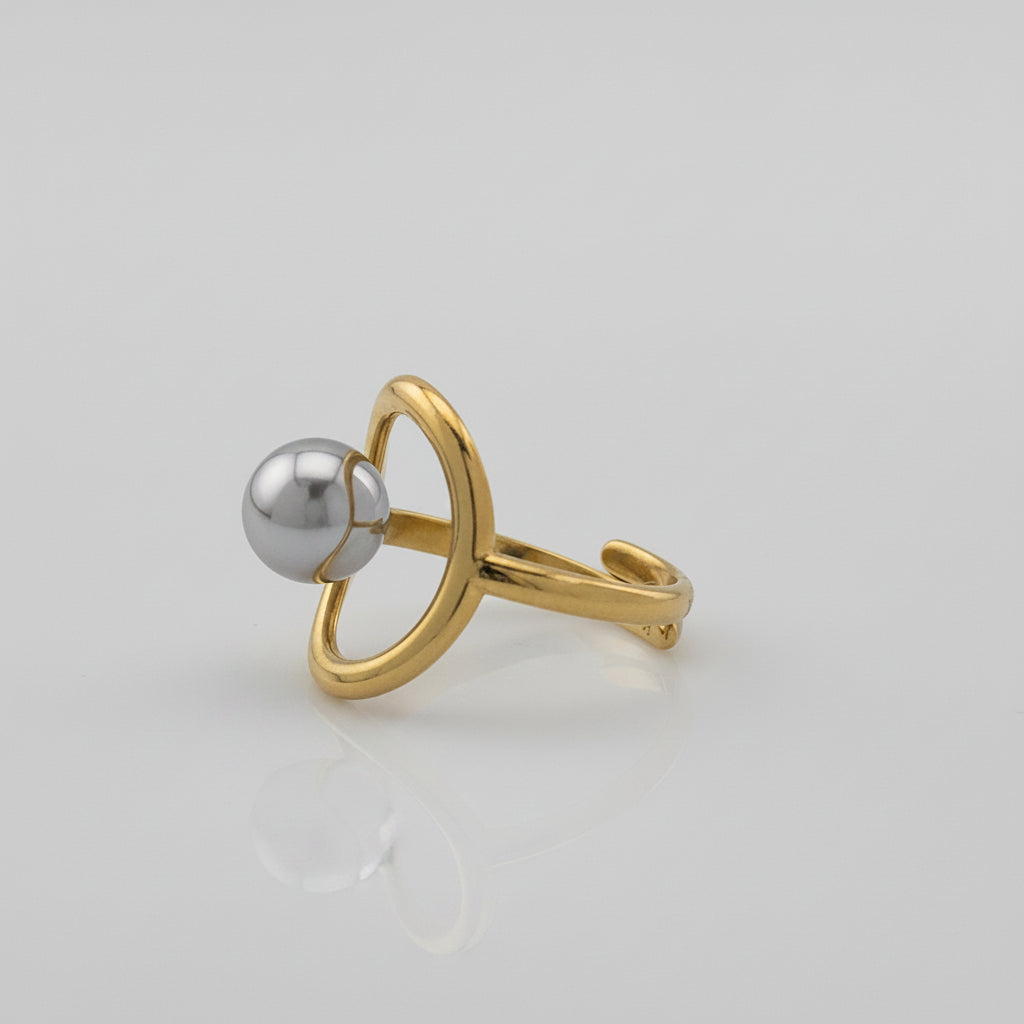 Gold ring with a silver sphere on a gray background