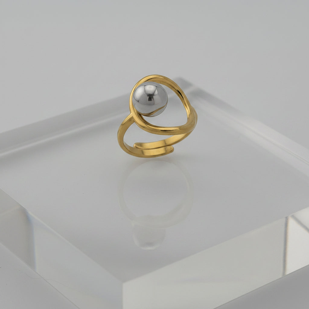 Gold ring with a central gray gemstone on a gray background